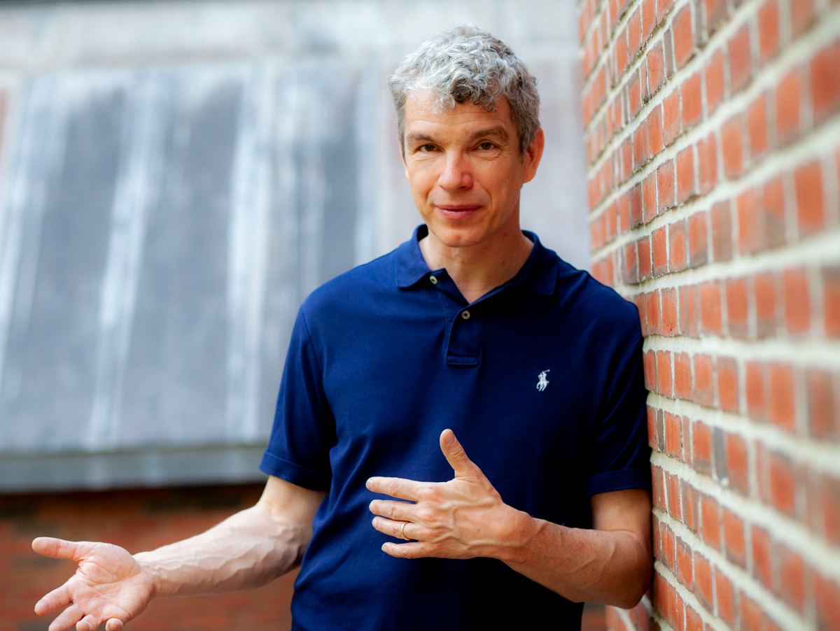 Morten Sorensen wearing a blue polo shirt leaning on a brick wall.